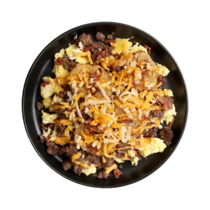 Brunch Burger Bowl with scrambled eggs, ground beef, hash brown rounds, bacon, shredded cheese, and sauce in a black bowl
