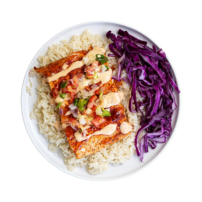 Firecracker Salmon with rice, shredded purple cabbage, pico de gallo, chipotle sauce, and sweet chili glaze on a white plate